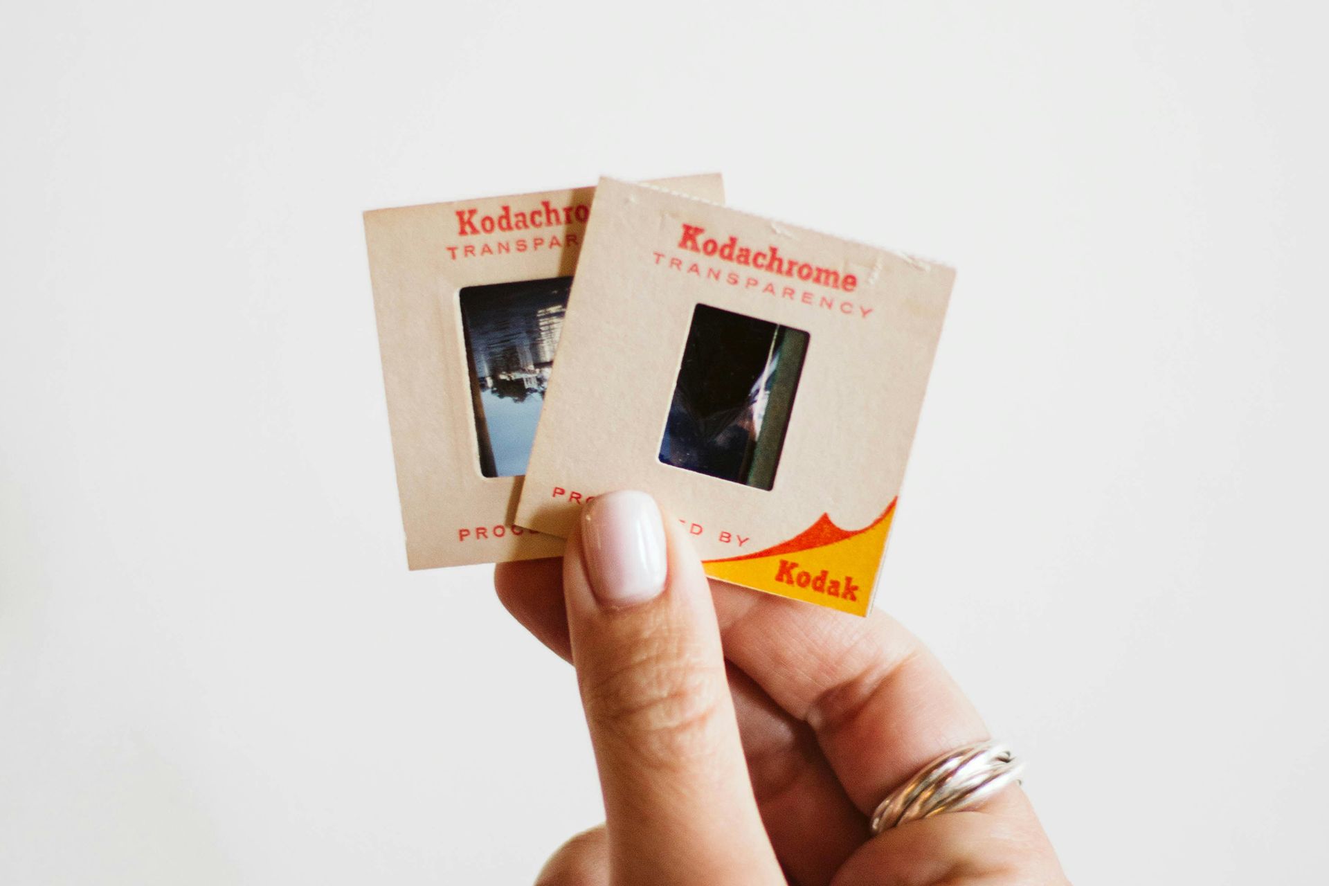 A person is holding two kodachrome slides in their hand.