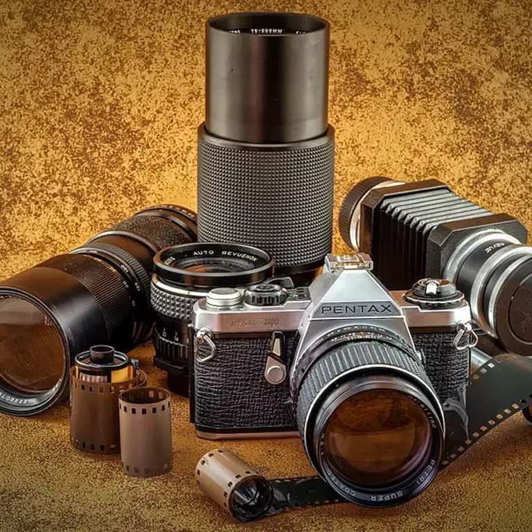 A pentax camera surrounded by lenses and film