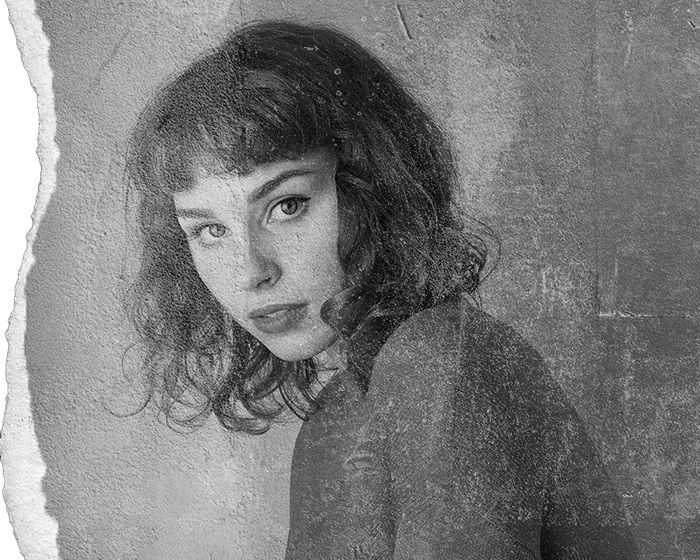 A black and white photo of a woman with curly hair looking at the camera.