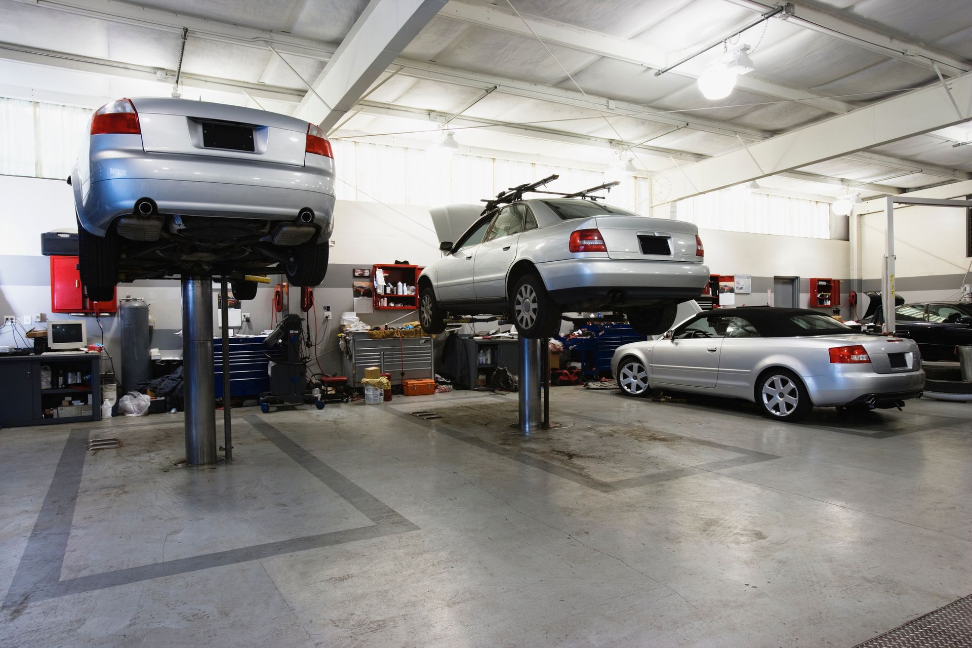 Two Cars Are Sitting on A Lift in A Garage | El Paso, TX | Jerry’s Auto Repair & Tire