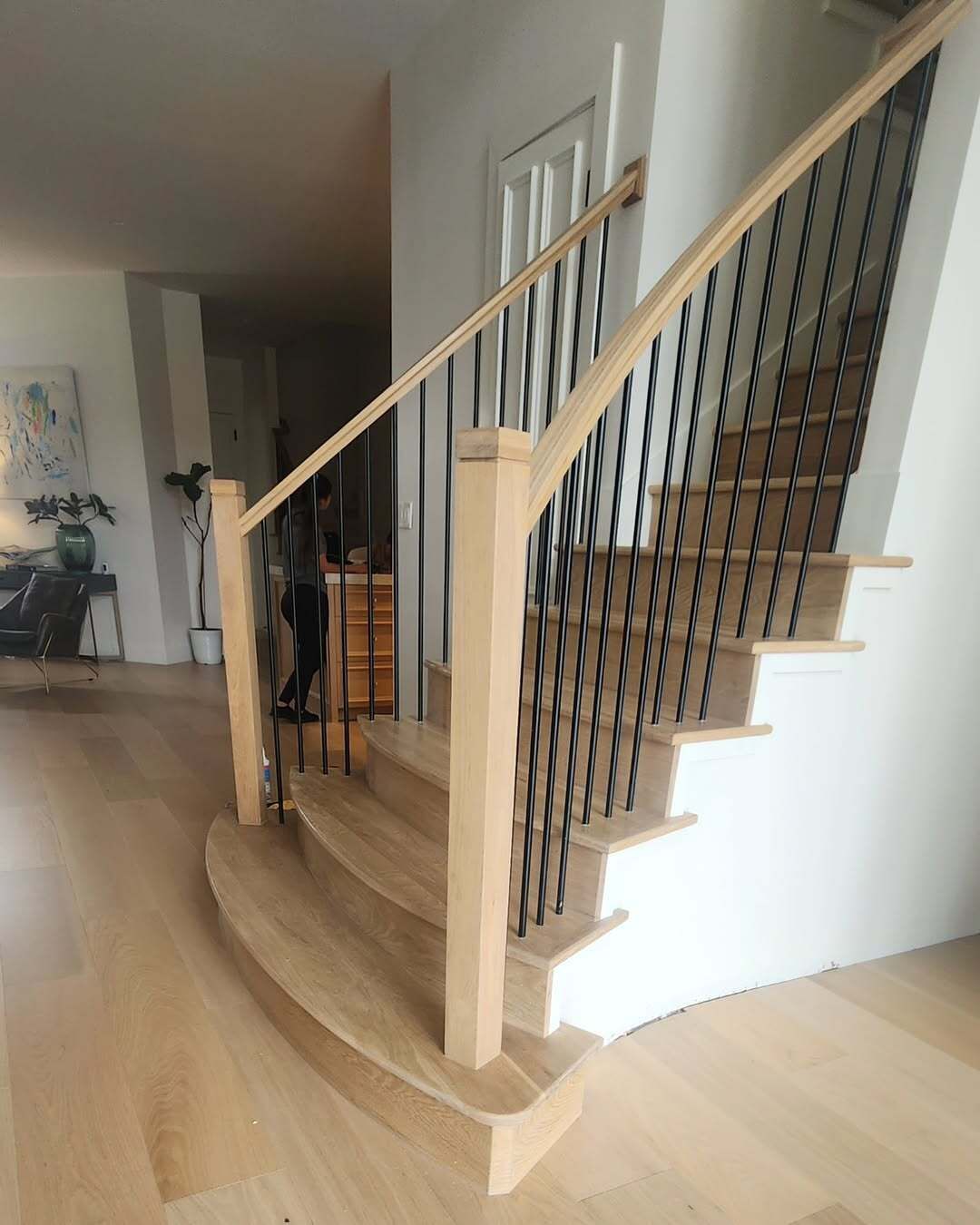 Curved wooden staircase with black cable railing in a modern home interior