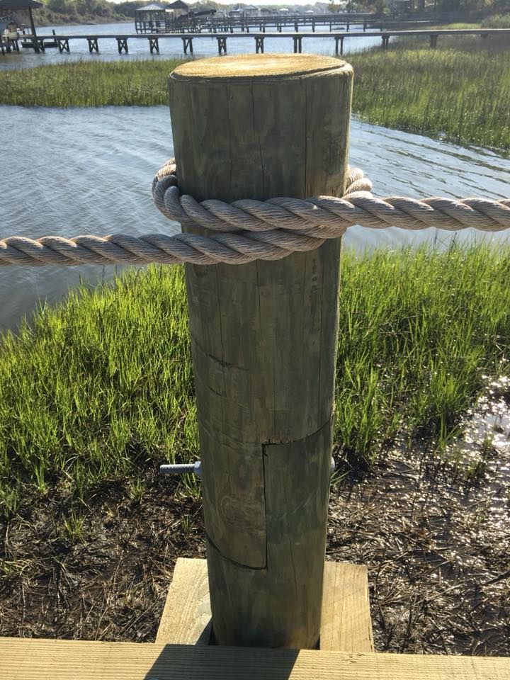 A wooden post with a rope around it is next to a body of water