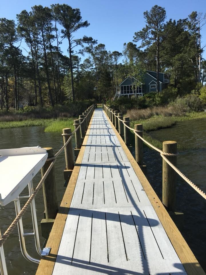 A wooden bridge over a body of water with a house in the background