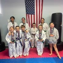 A group of children are posing for a picture in front of an american flag.