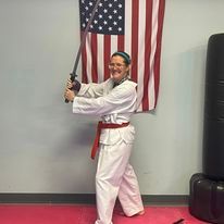 A martial arts student is wielding a sword in front of an American flag