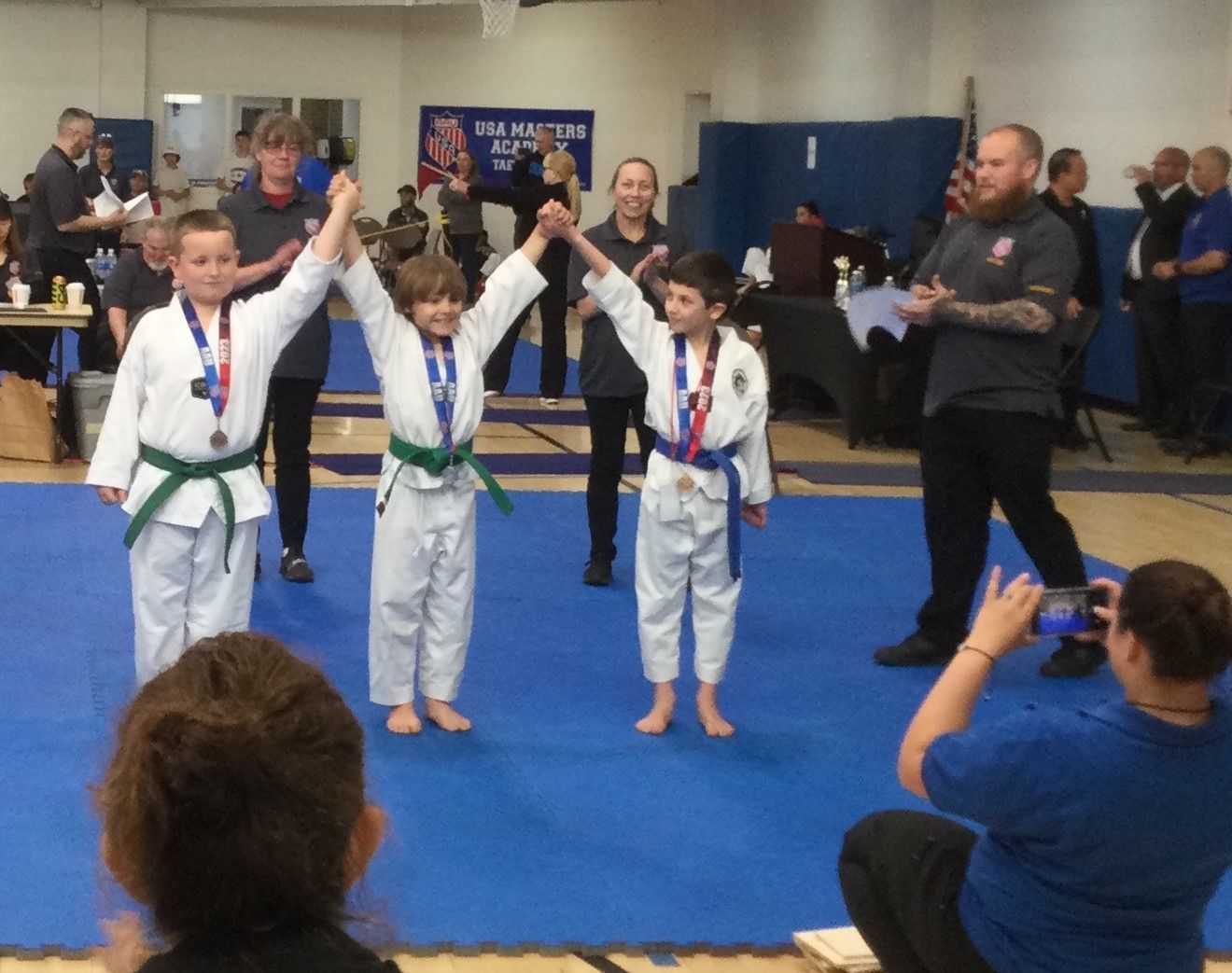 A woman is taking a picture of a group of kids in karate uniforms
