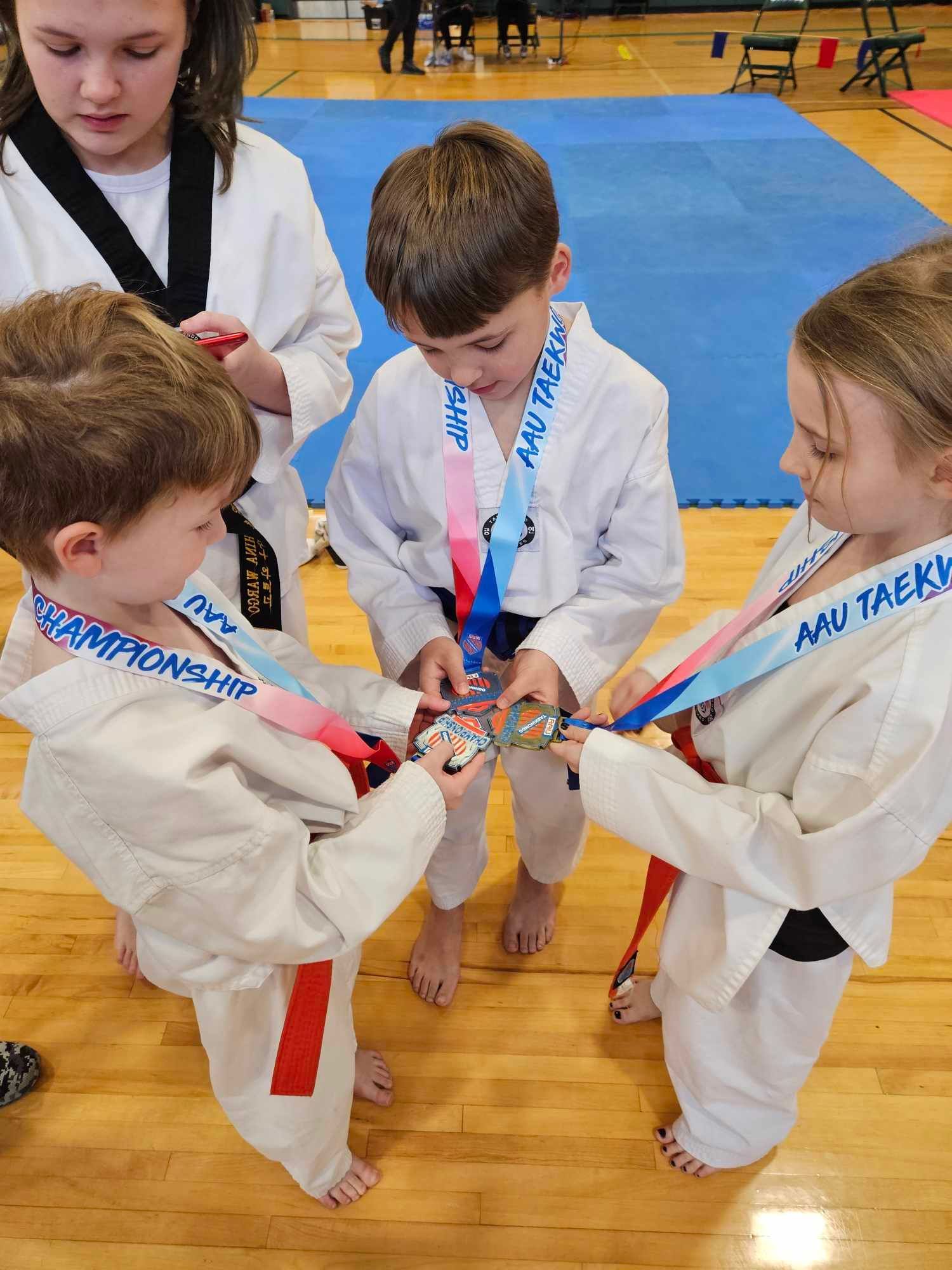 A group of young children are standing in a circle holding medals.