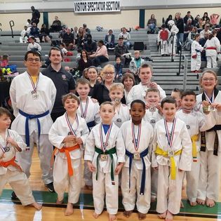 A group of kids are posing for a picture in front of a sign that says visitor spectator section