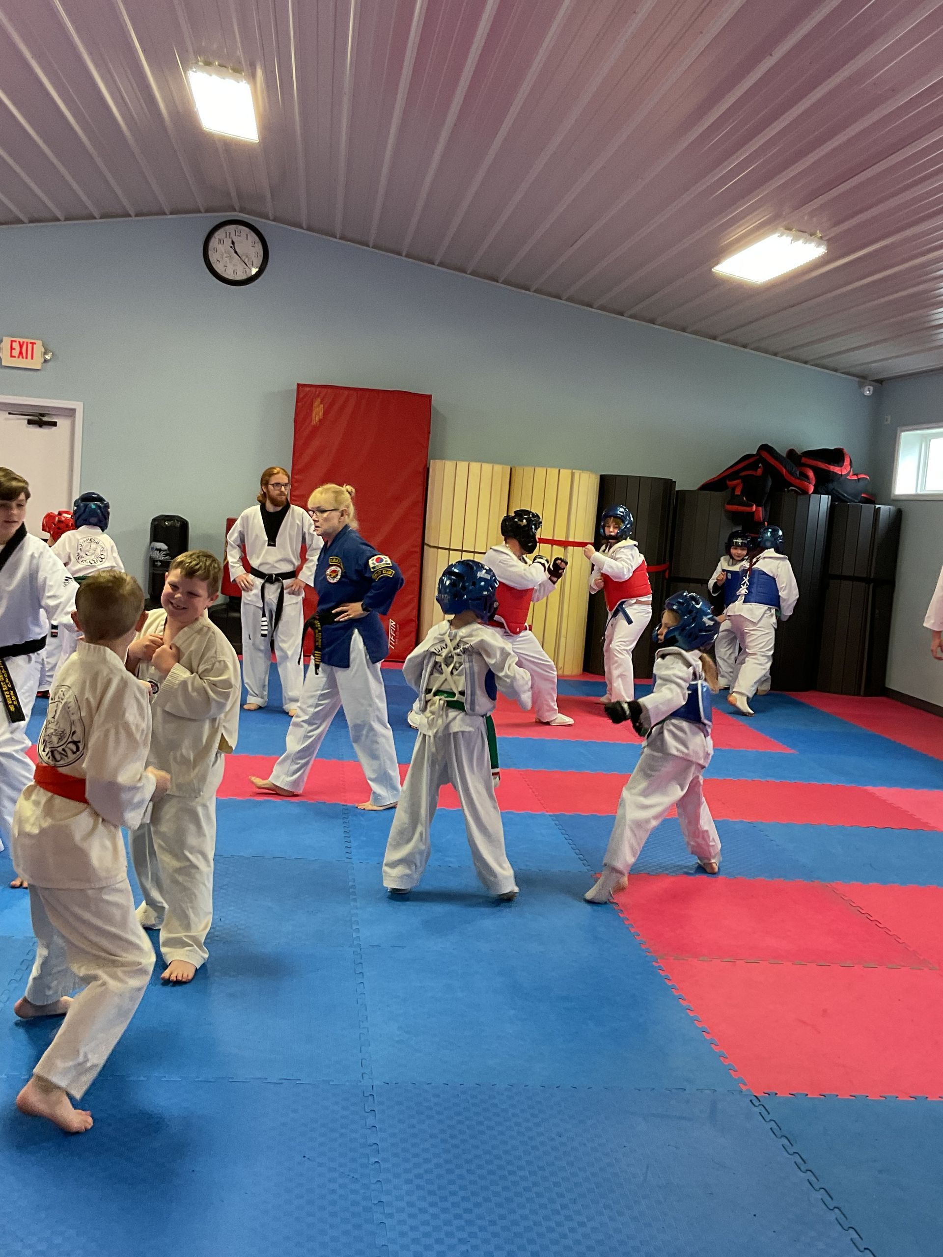 A group of children are practicing martial arts in a gym.