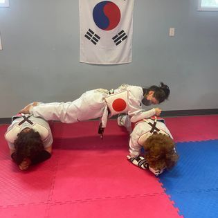 A group of people are doing push ups on a mat in a room.