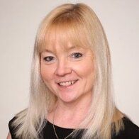 A woman with blonde hair and a black shirt is smiling for the camera.