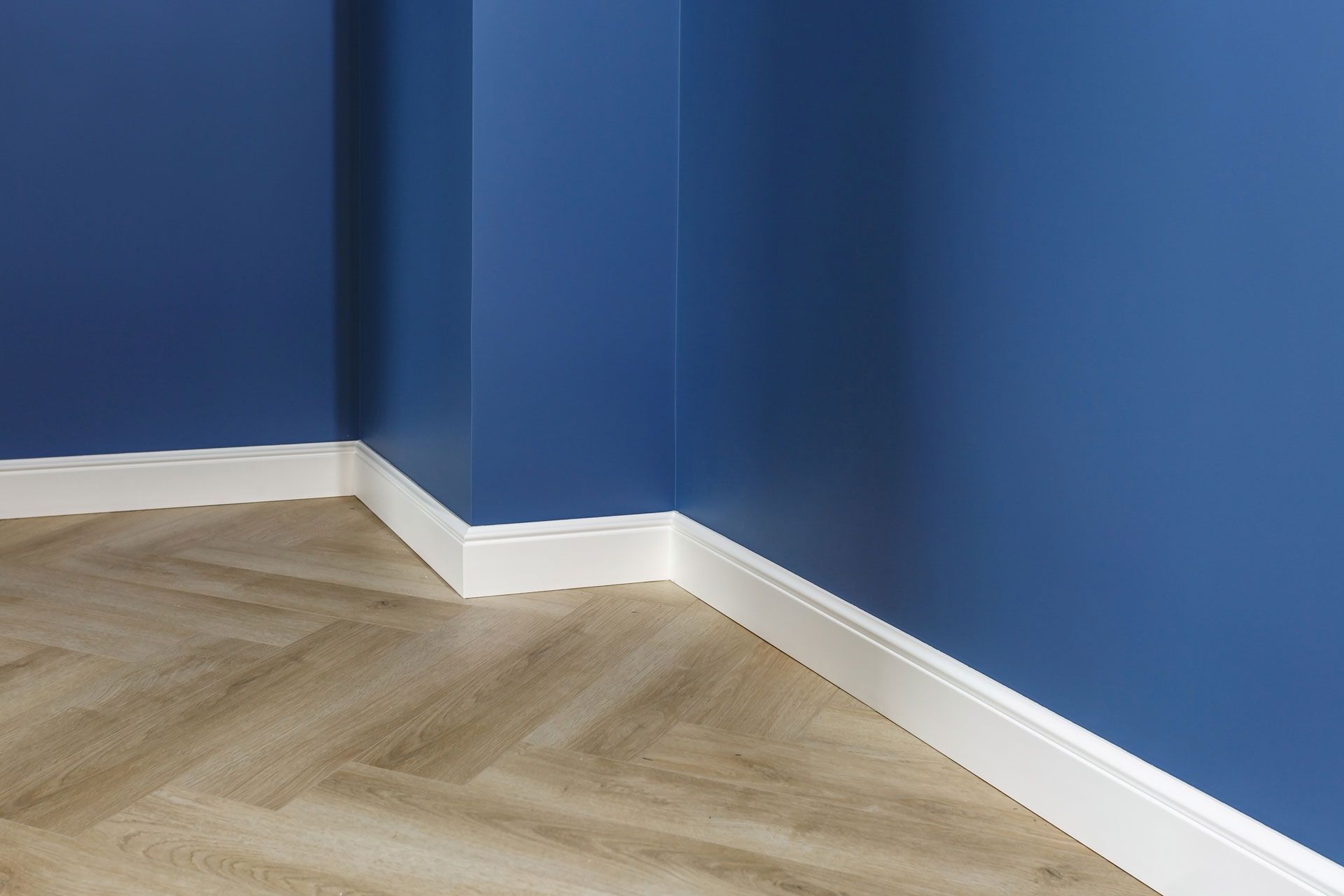 Blue walls meet white baseboards and light-colored herringbone floor.