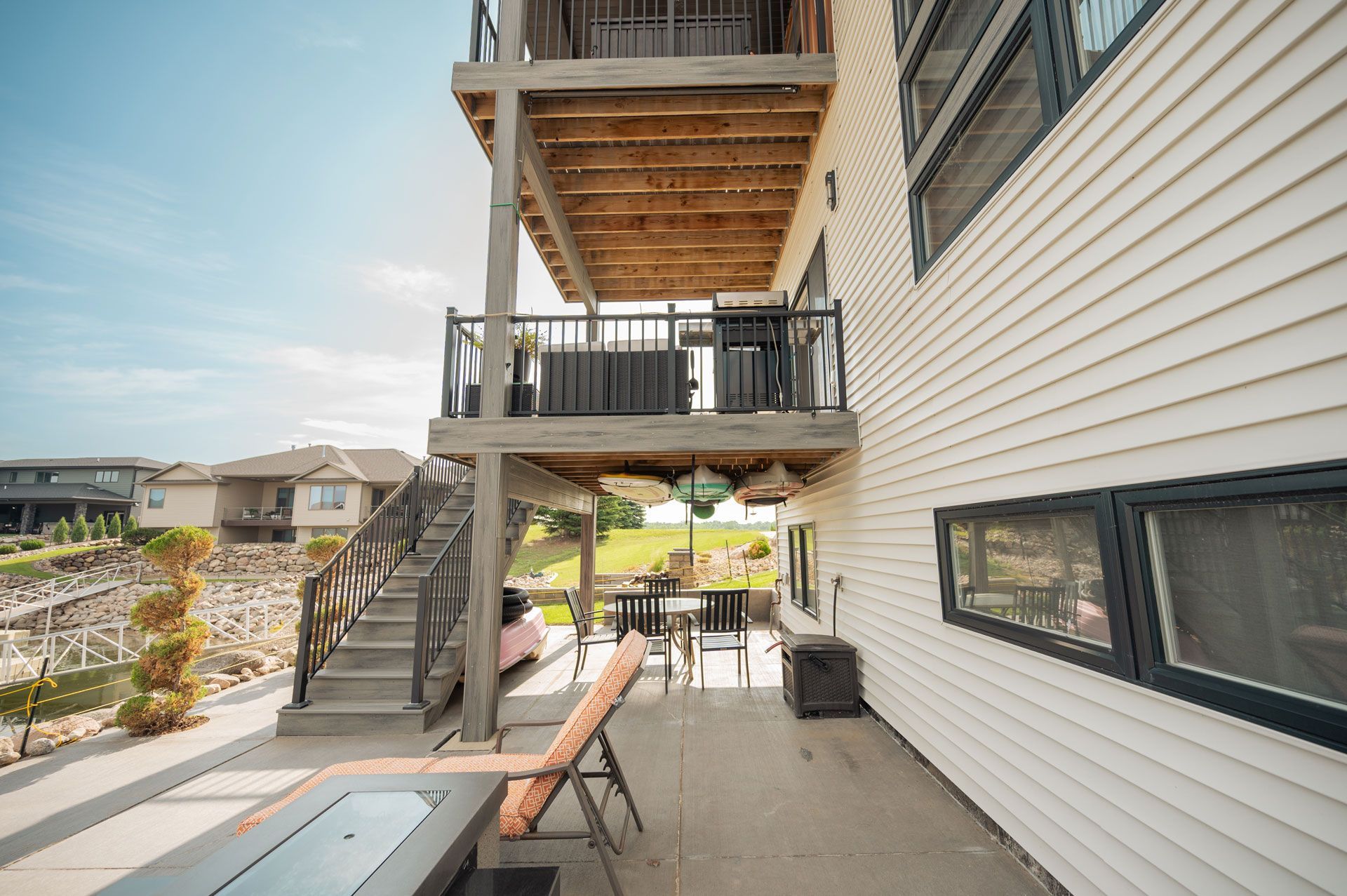 Exterior view of a multi-level house with a deck, stairs, and outdoor furniture.