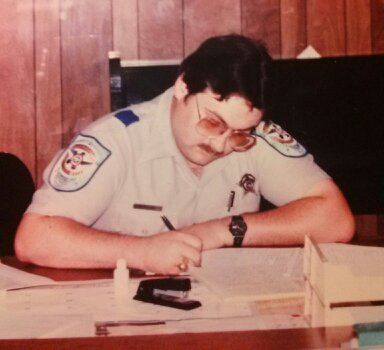 A police officer is sitting at a desk writing on a piece of paper