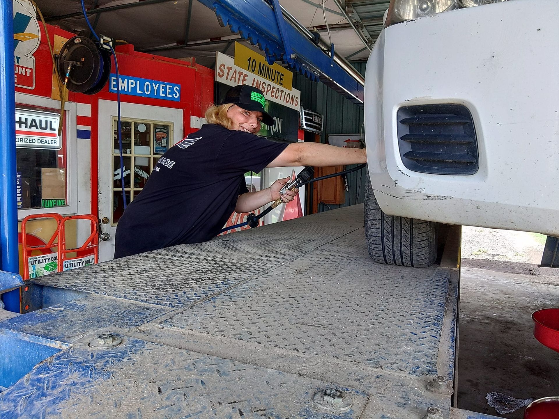 A woman is working on a truck in front of a sign that says employees