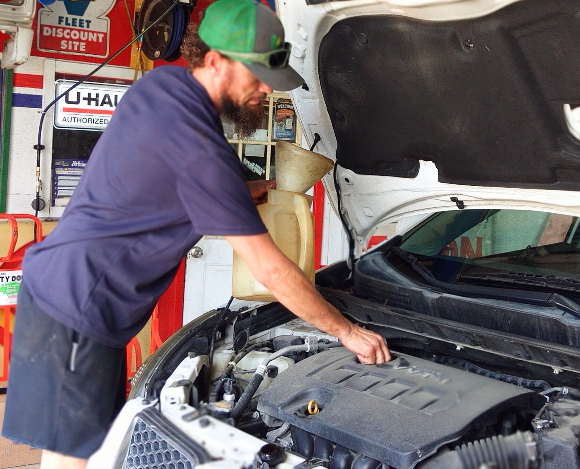 A man is working on the engine of a car with the hood open