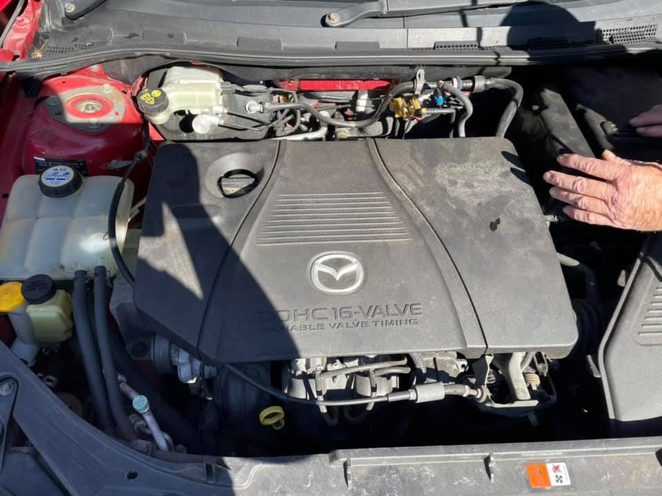 A man is looking under the hood of a Mazda car — AZNU Automotive In Lismore, NSW