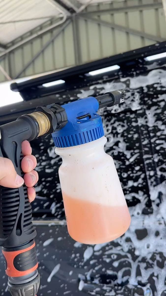 A Person Is Holding A Hose With A Bottle Of Liquid In It — AZNU Automotive In Lismore, NSW