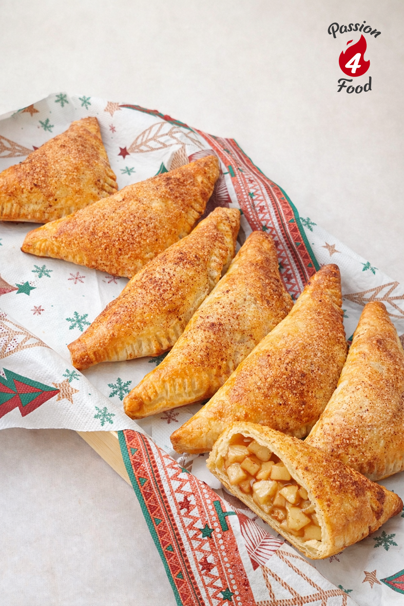 Goudgeel gebakkenppellappen op kerstservetten. Eén appelflap is opgesneden, zodat je de inhoud ziet.