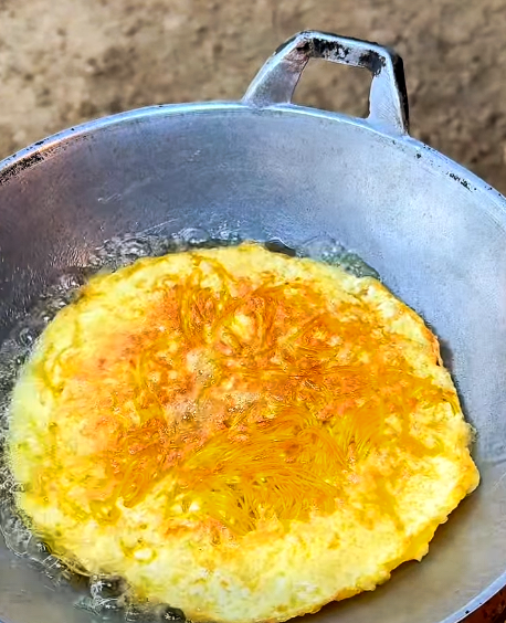 Goudbruin gebakken omelet in een metalen pan