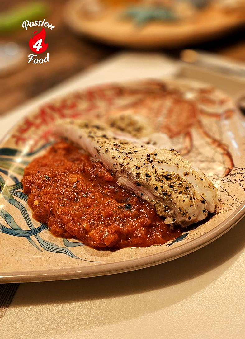 Corvinafilet op Spaans bord met vismotief op een laagje paprika-tomaatsaus.
