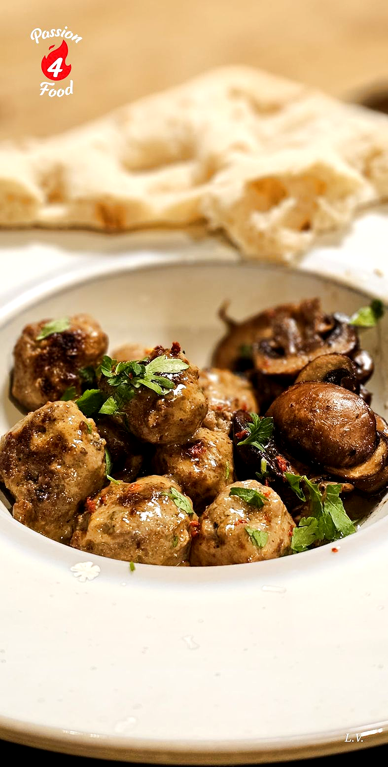 Gehaktballetjes in truffelroomsaus op wit bord. met pinsabrood.