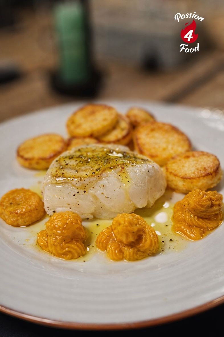 Gekonfijte skrei, beter bekend als winterkabeljauw, op een wit bord met toefjes pompoencreme.