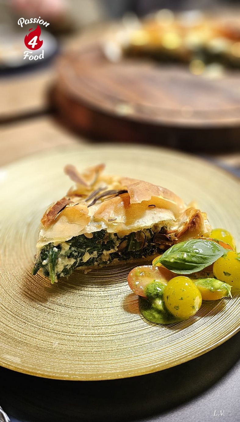 Punt Griekse spinazie-fetataart op goudkleurig bord met een frisse kleurige tomatensalade.