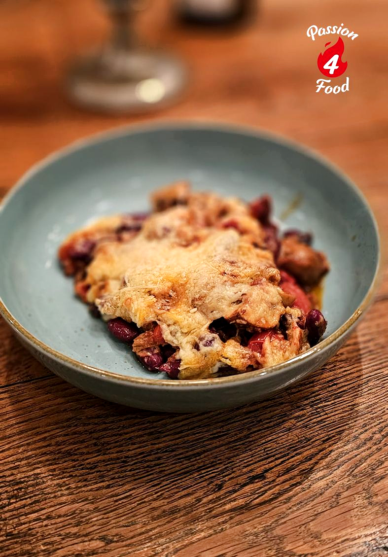 Mexicaanse vegetarische bonenschotel op bord met gesmolten kaas.