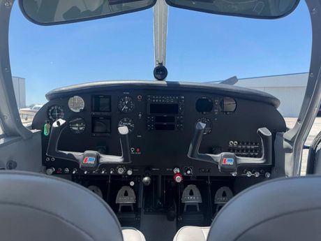View from a small airplane cockpit with controls, gauges, and sky visible through the windshield