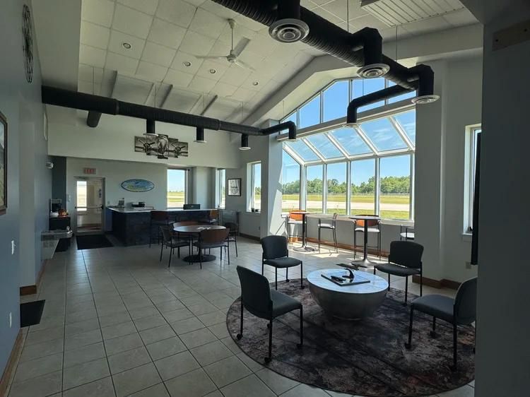 Modern lounge with black chairs, round table, and large windows overlooking a bright landscape