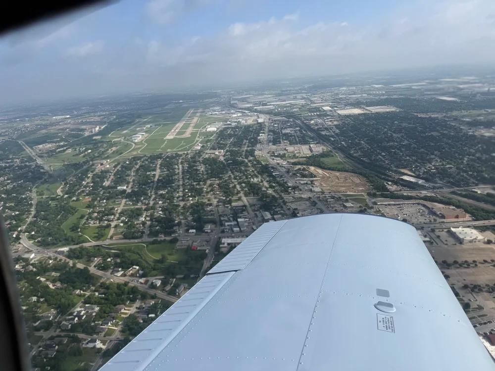 Aerial view from an airplane wing over a city and runway on a hazy day