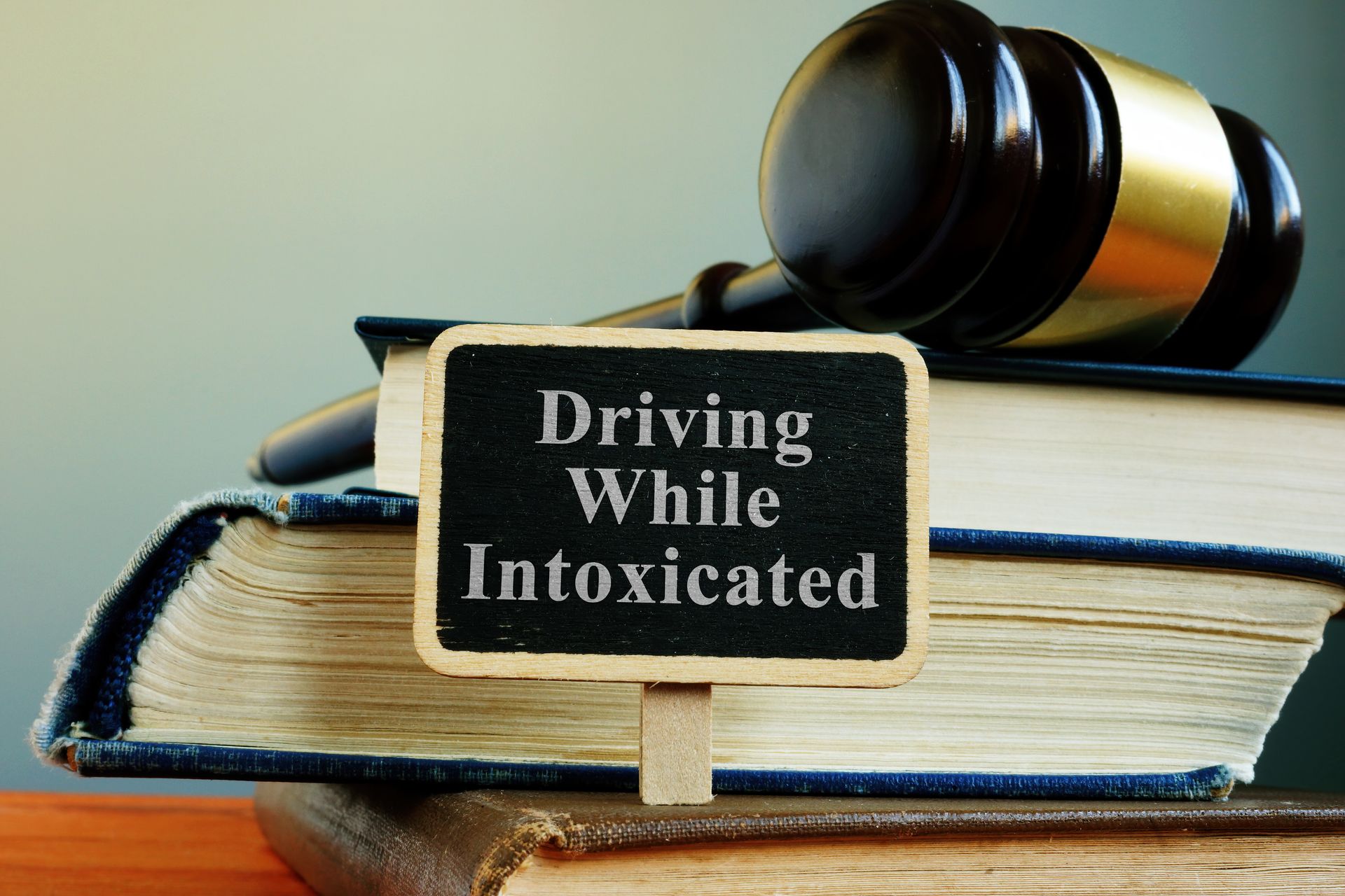 Gavel resting on law books beside a sign reading “Driving While Intoxicated.”