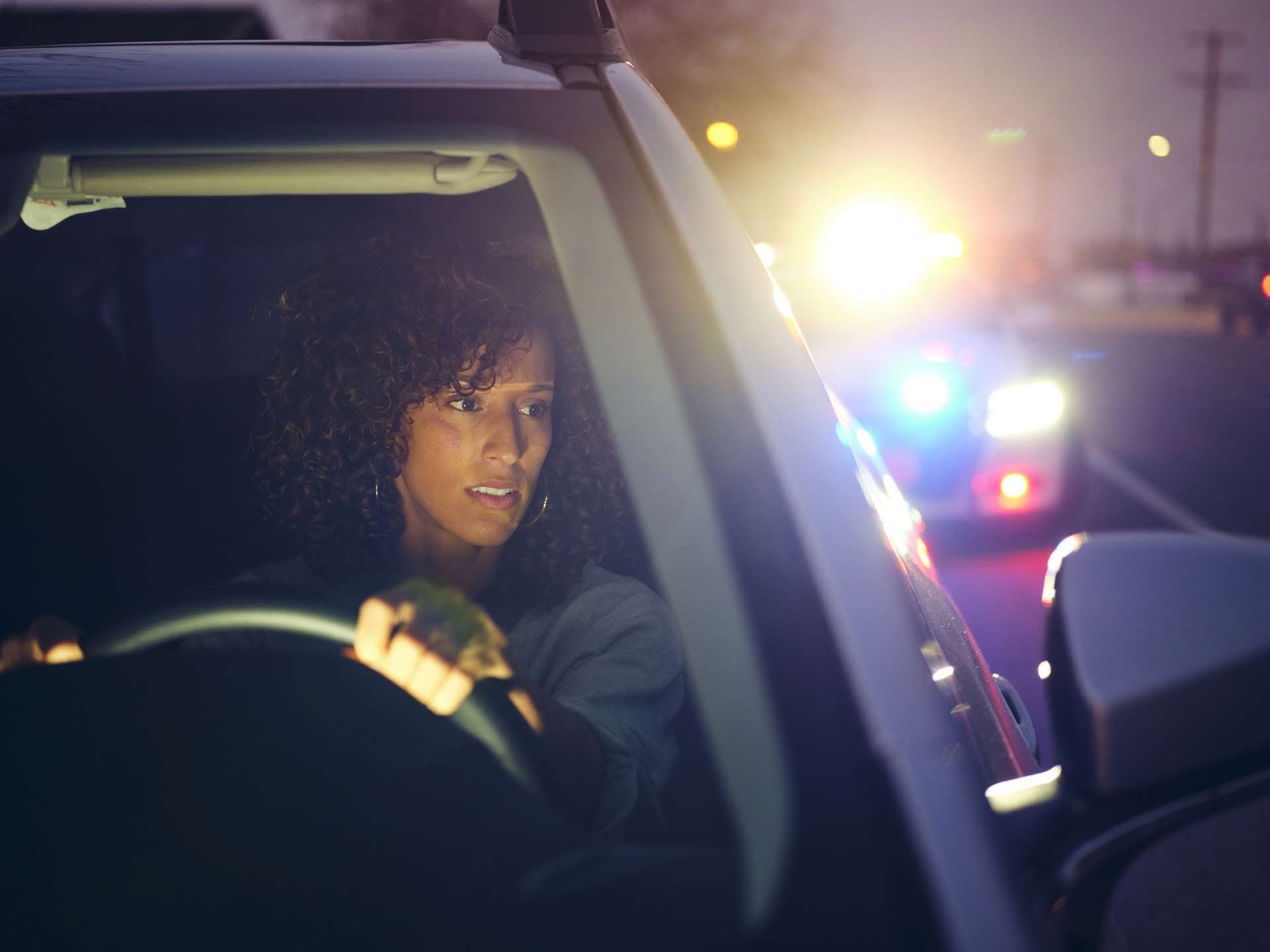 A young woman, being stopped by police at night for a traffic violation, highlighting DWI bail bonds.