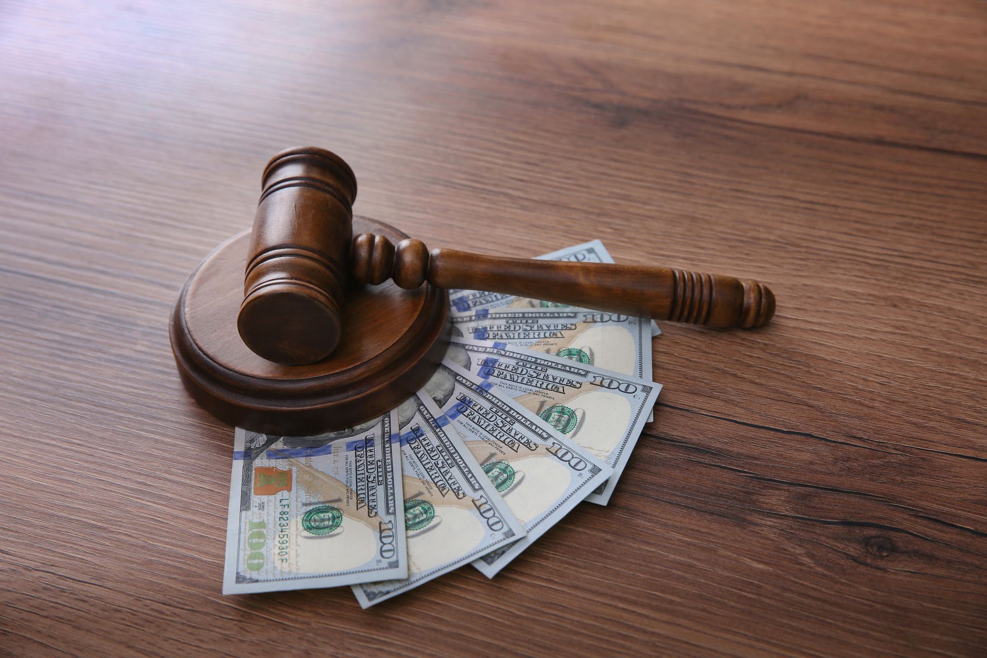 Wooden gavel on money, representing legal and financial themes.