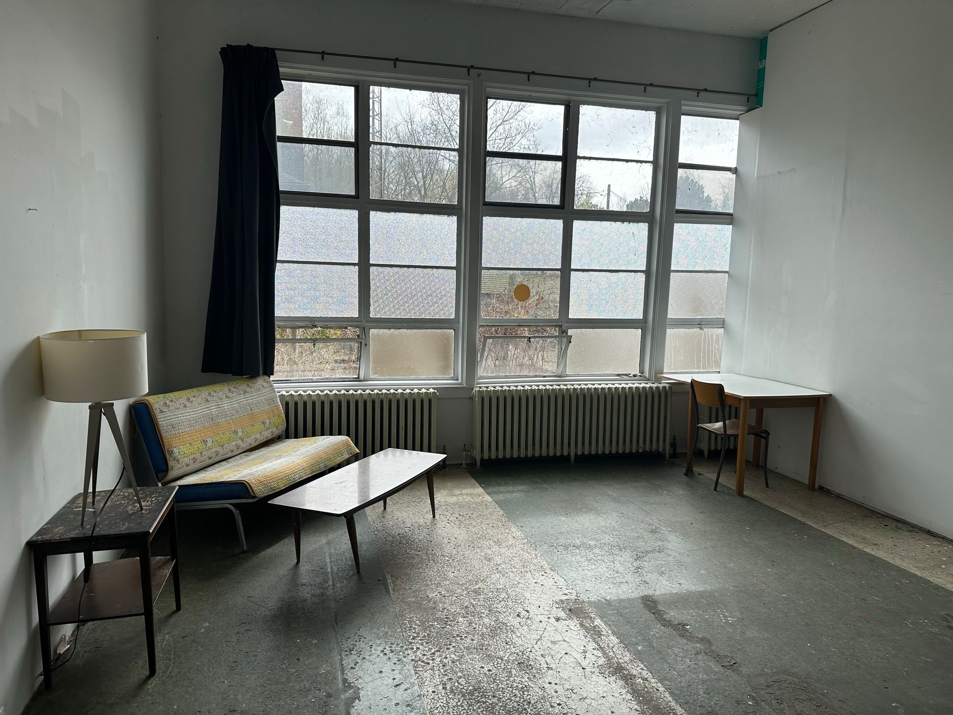 Artist studio with a couch, table, and large window.