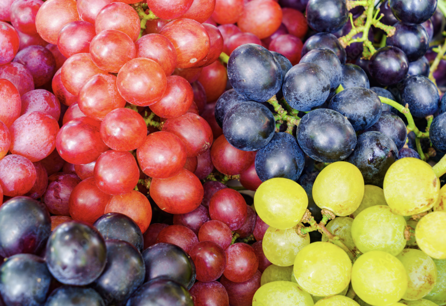 Un racimo de uvas de diferentes colores está sobre una mesa.