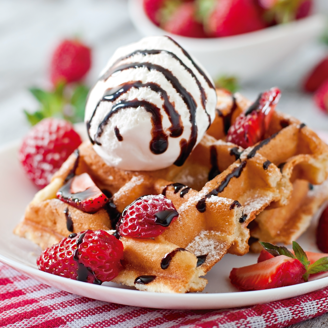 Un gofre con fresas y helado en un plato.