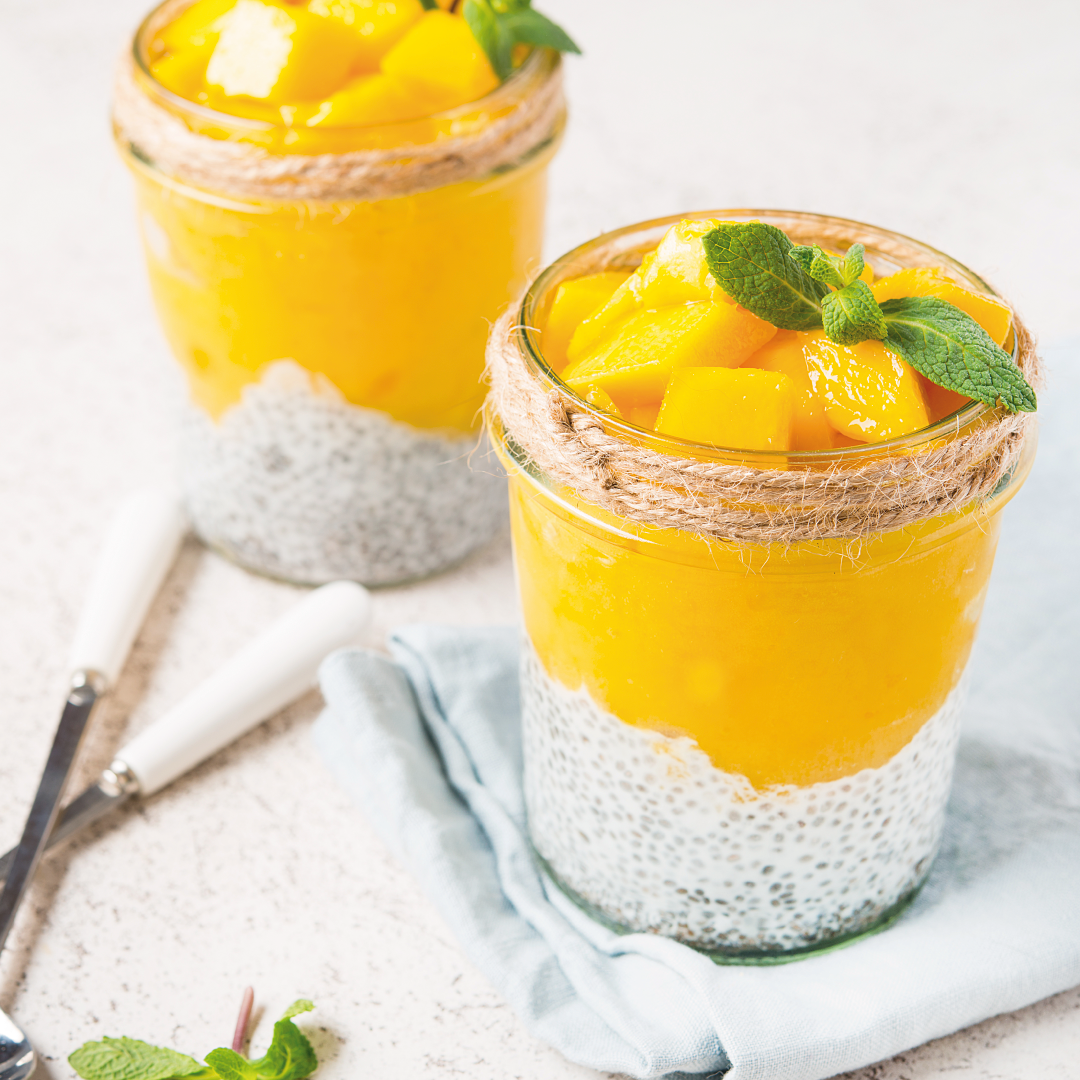 Dos frascos de pudín de semillas de chía con mango y menta sobre una mesa.