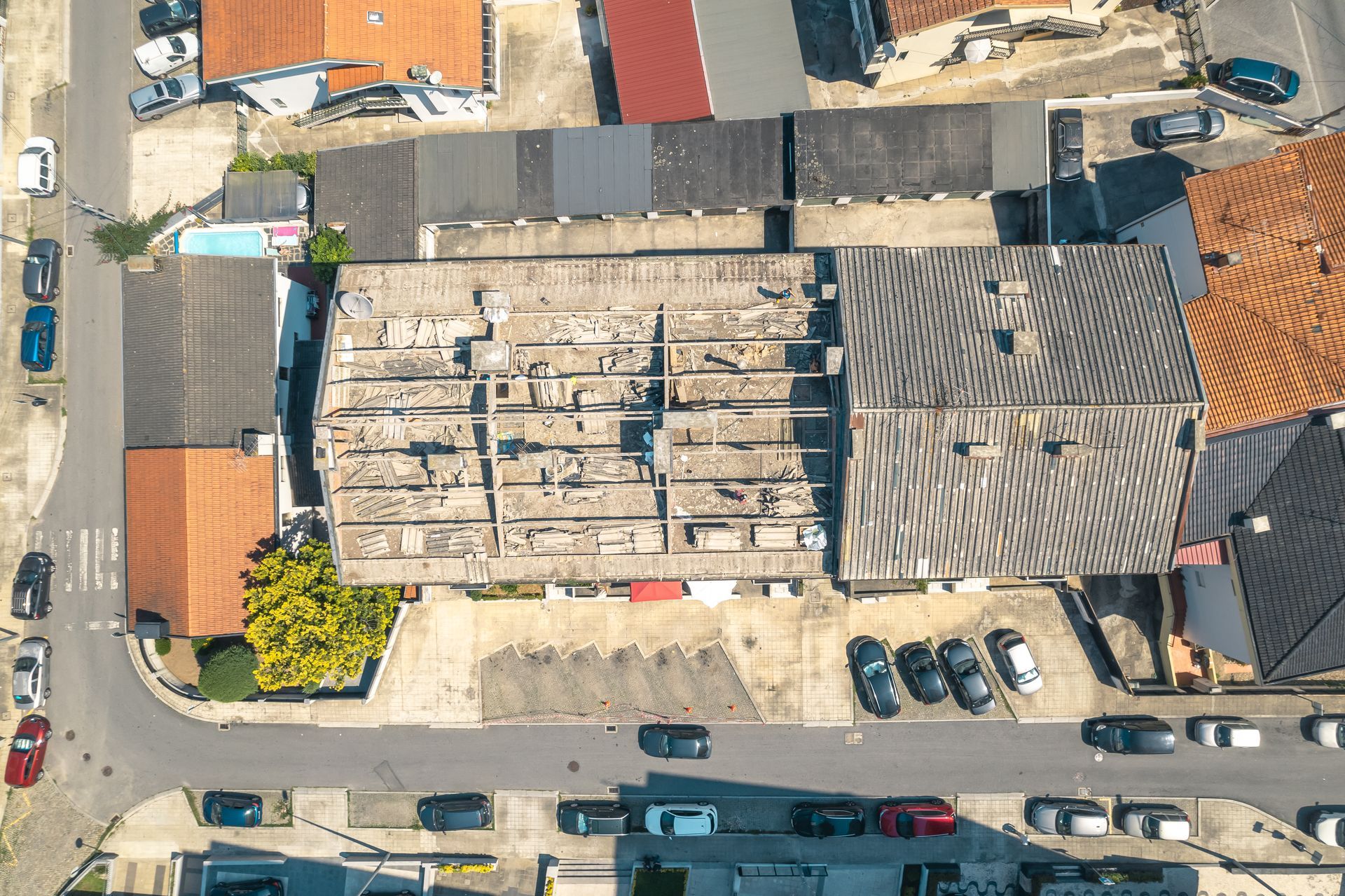 Uma vista aérea de um prédio com muitos carros estacionados na frente dele.