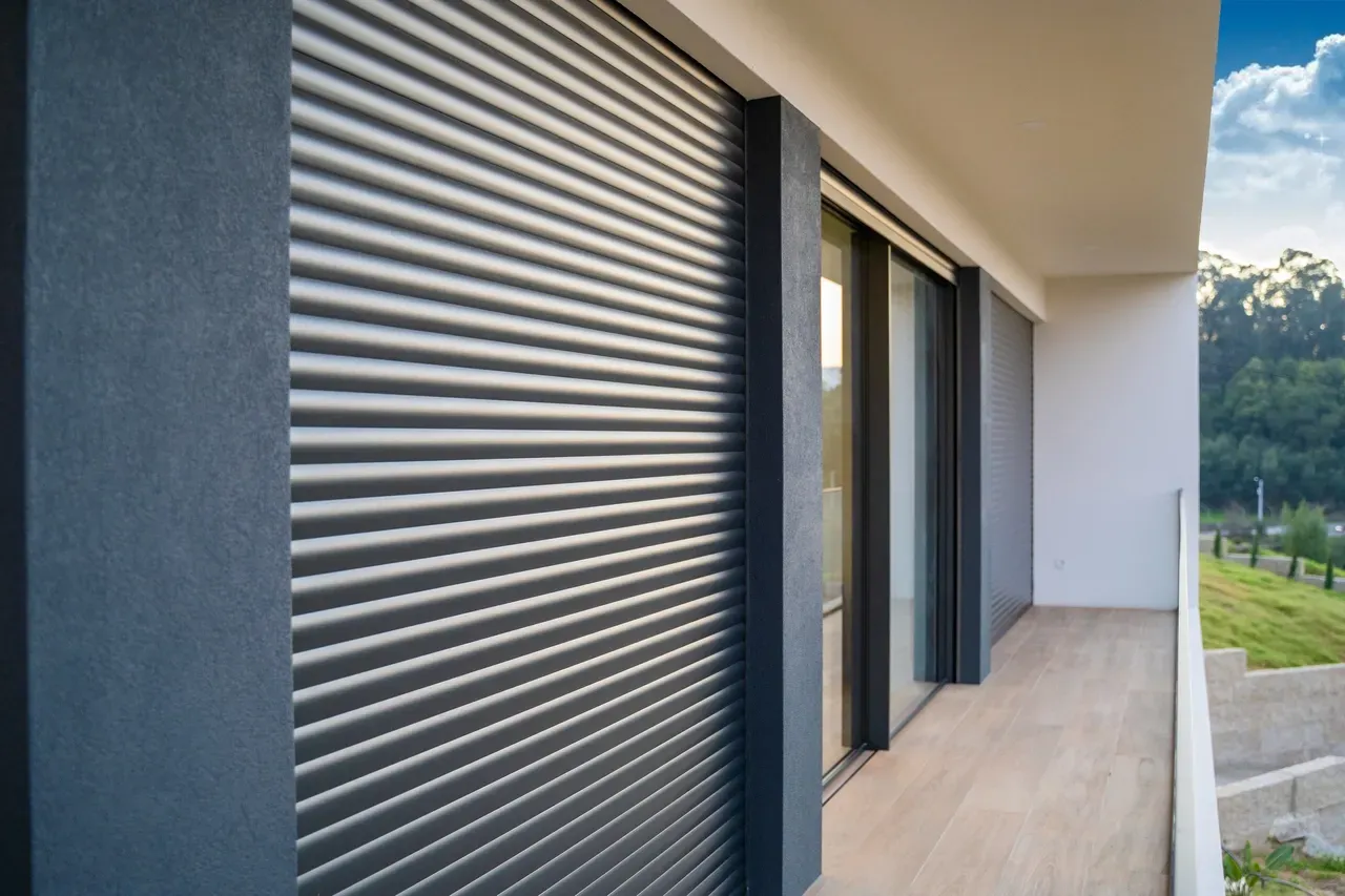 Exterior de um edifício moderno com Estores e persianas cinzentas cobrindo uma janela.