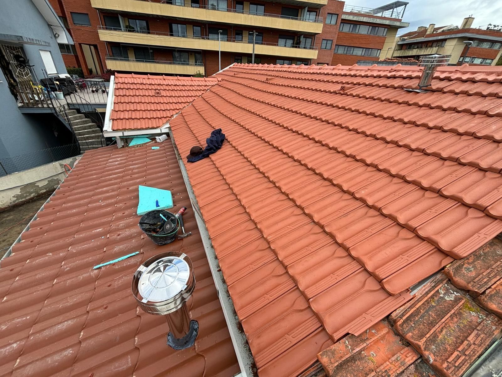 Um telhado com telhas vermelhas cerâmicas e uma chaminé.