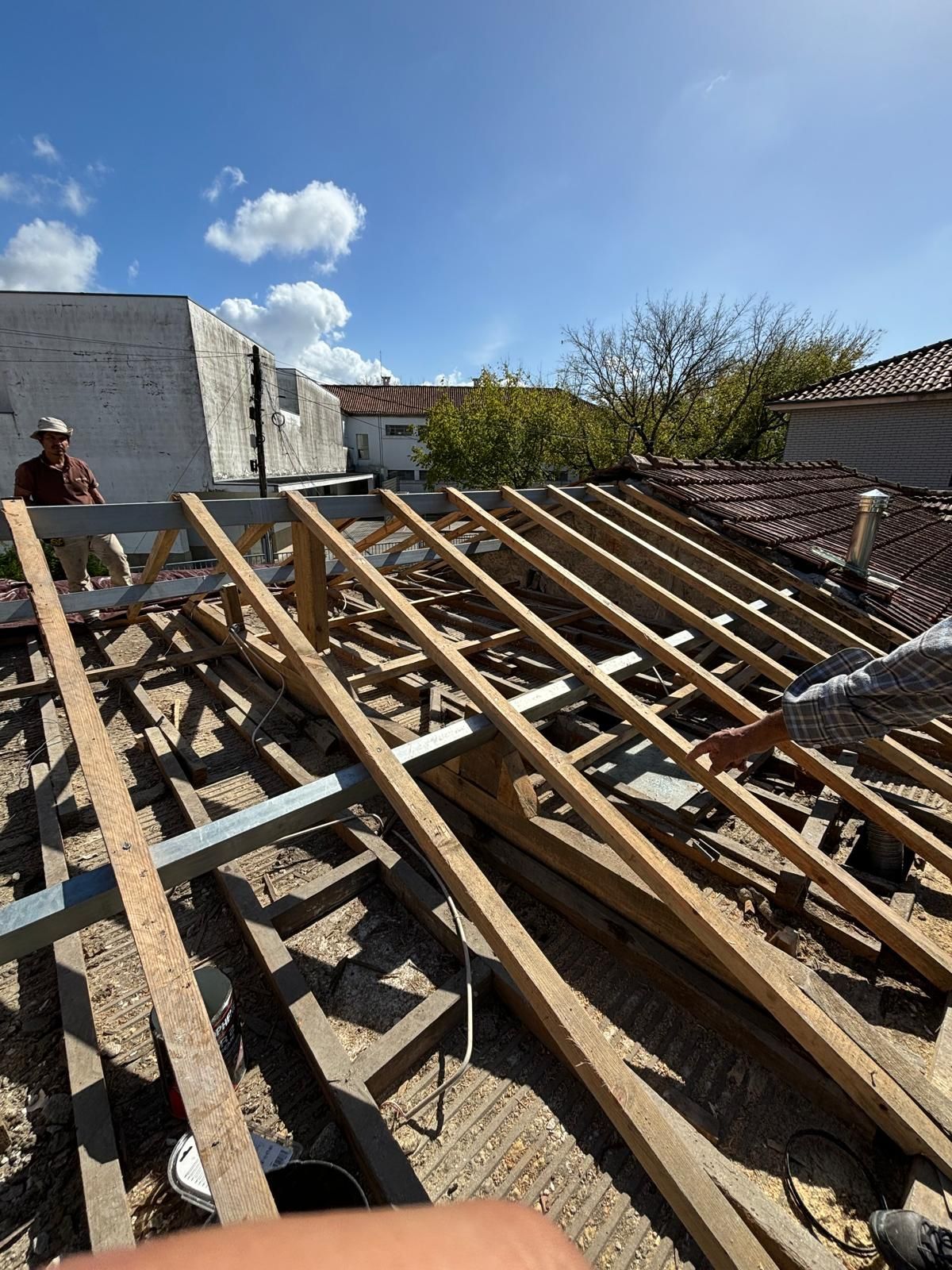 Um homem está de pé no topo de uma pilha de vigas de madeira.