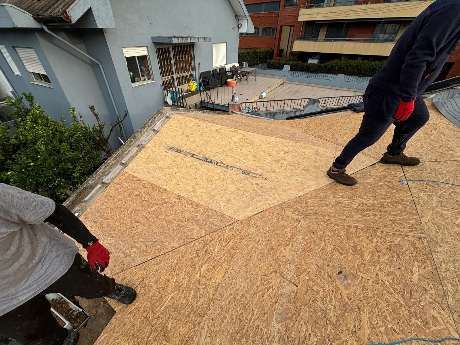 Duas pessoas estão trabalhando no telhado de uma casa.