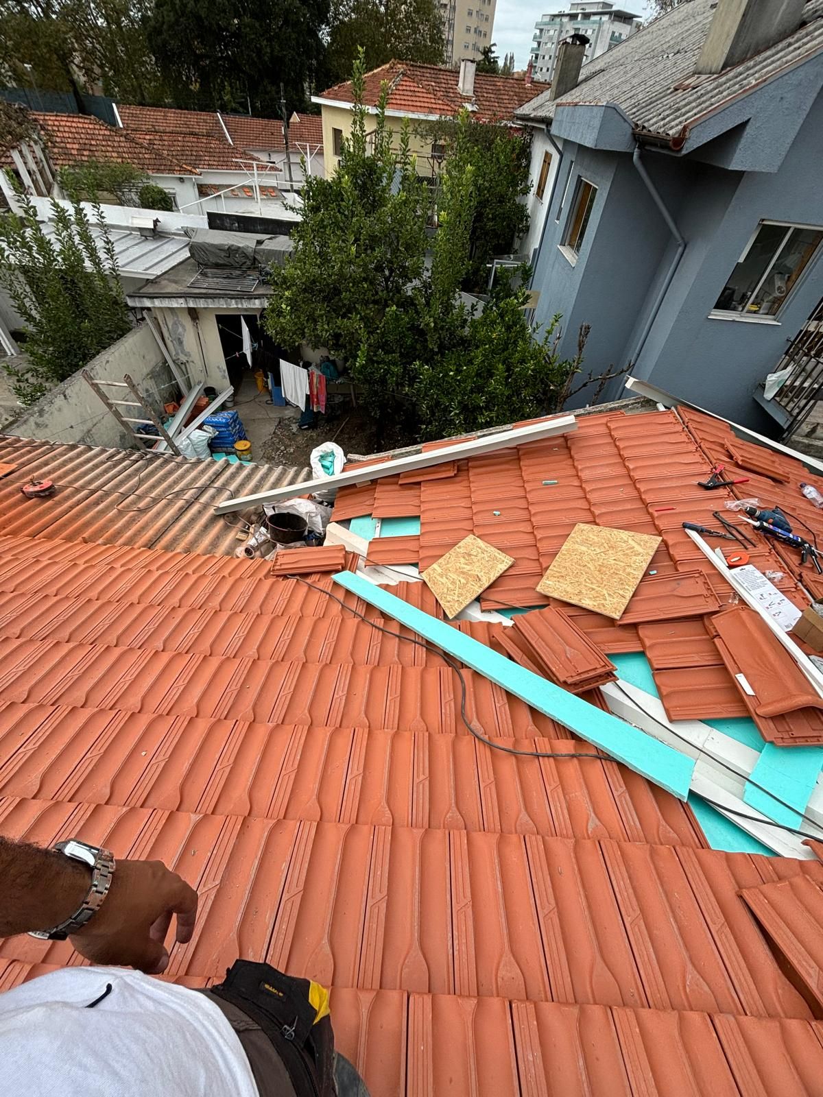 Um homem está em pé no topo de um telhado de telhas cerâmicas marselha..