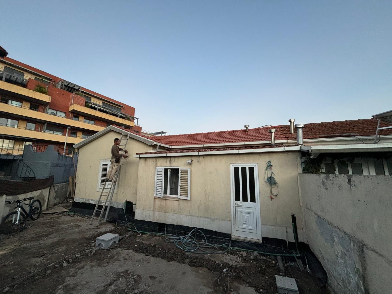 Um homem está em pé em uma escada em frente a uma casa.