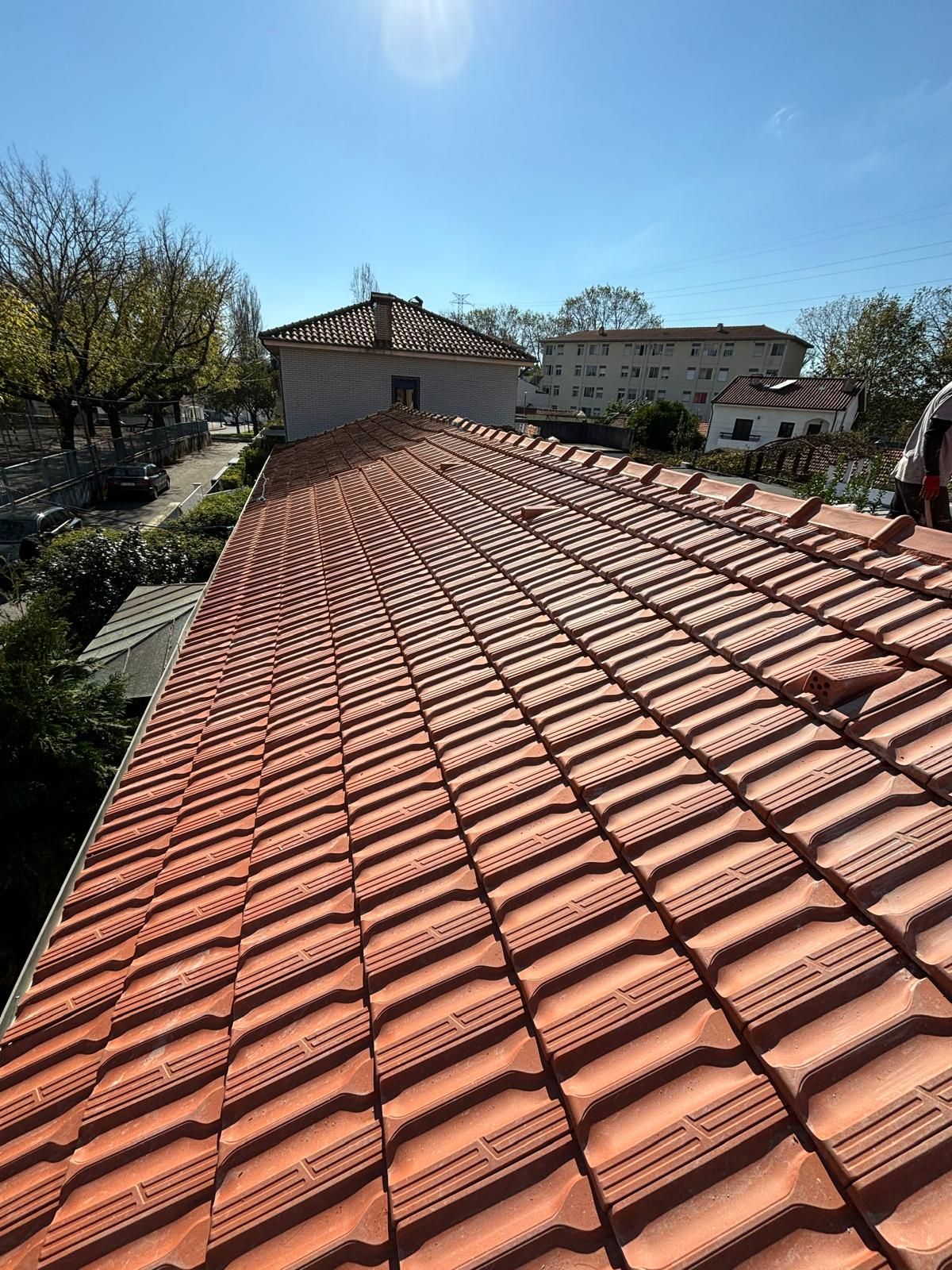 Um homem está trabalhando no telhado de uma casa com telhas cerâmicas marselha.