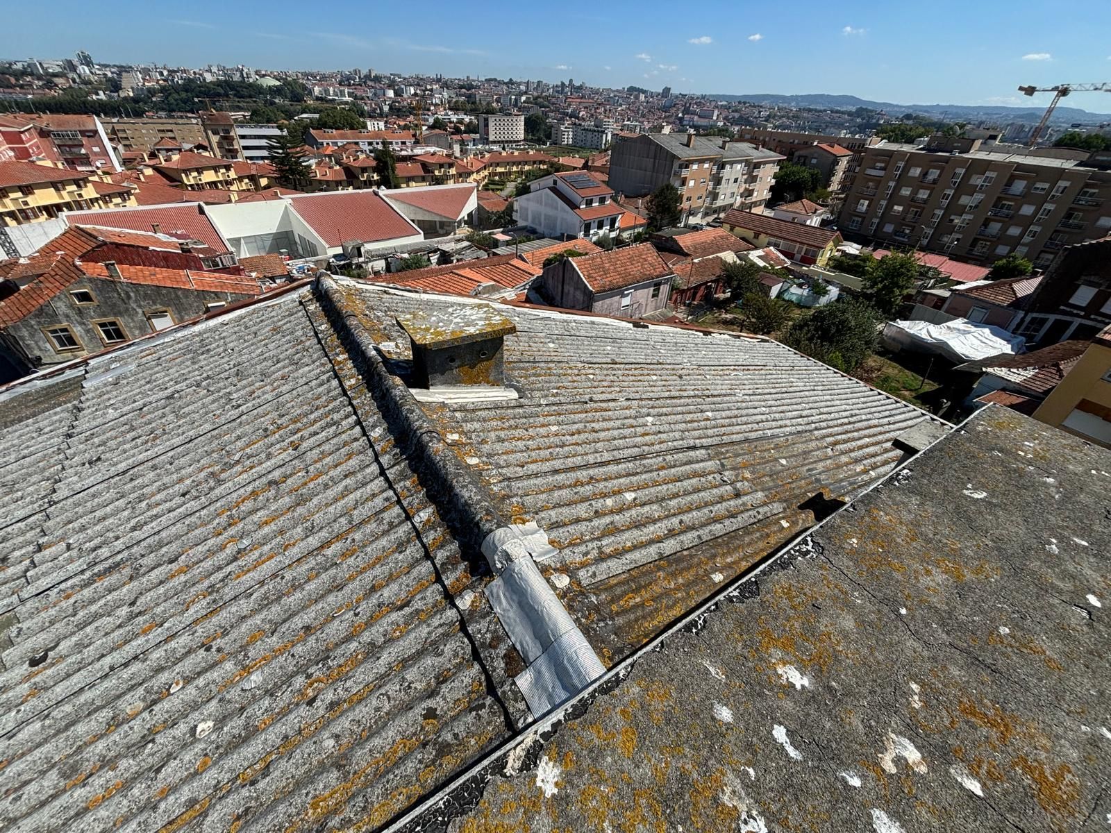 Uma vista aérea de um telhado fibrocimento amianto com uma cidade ao fundo.