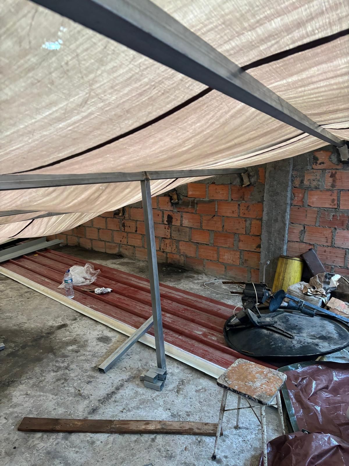 Um telhado com uma lona e uma parede de tijolos ao fundo.