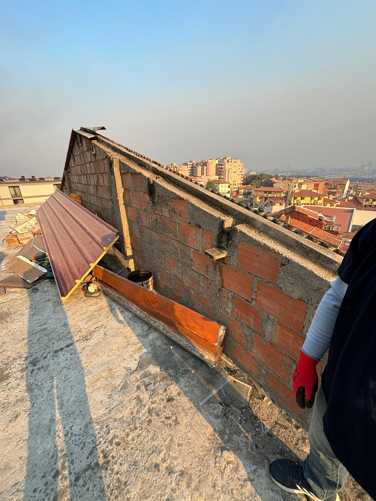 Uma pessoa está em pé no topo de um telhado próximo a uma parede de tijolos.